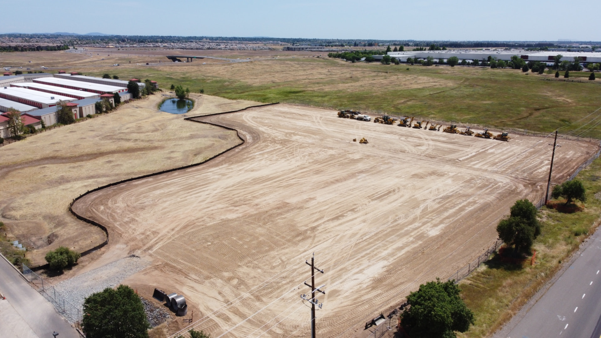 Aerial view of a graded commercial pad with a line of Lane Built Inc. heavy equipment in Northern California