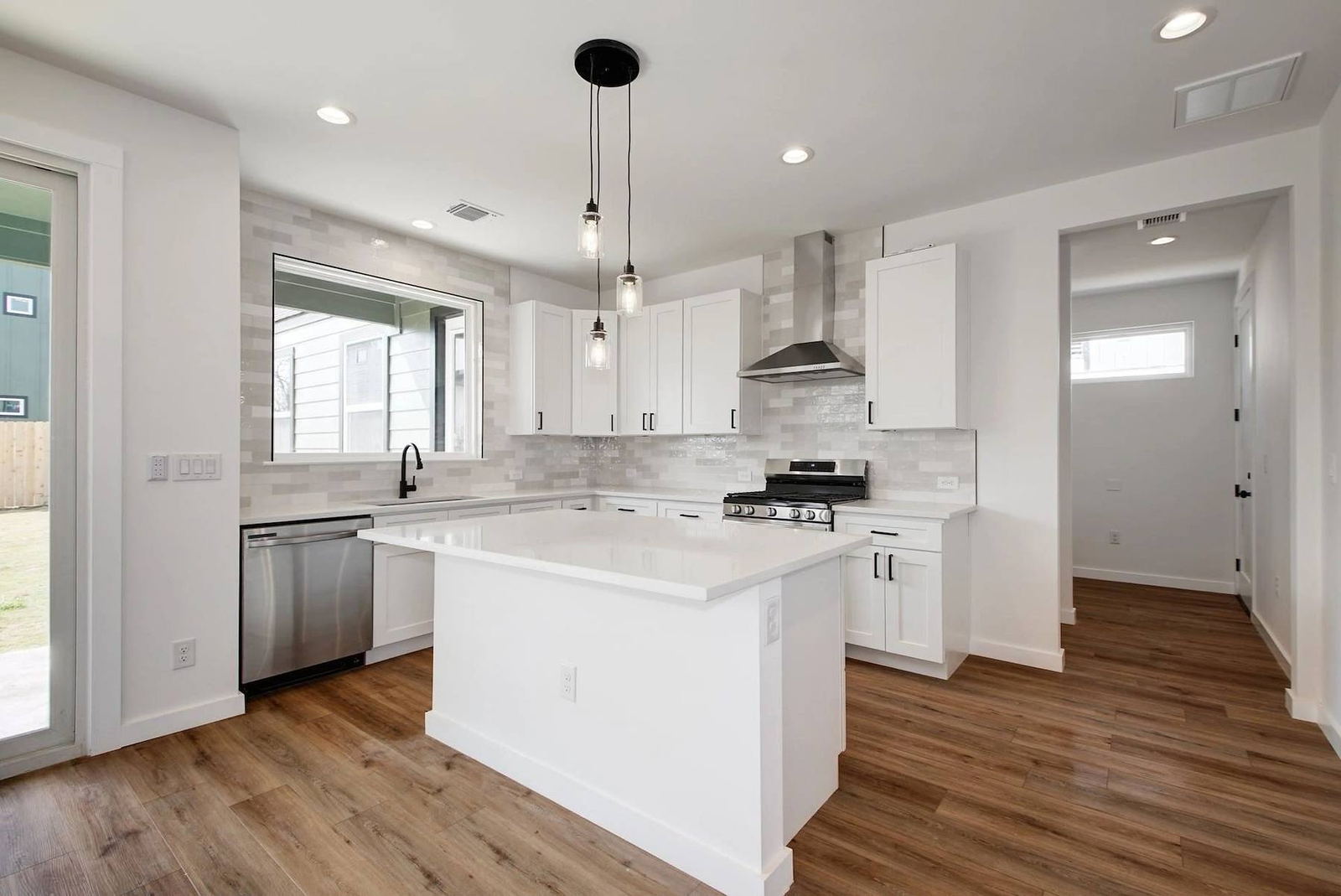 White shaker kitchen with waterfall island and stainless appliances in a Northern California custom home
