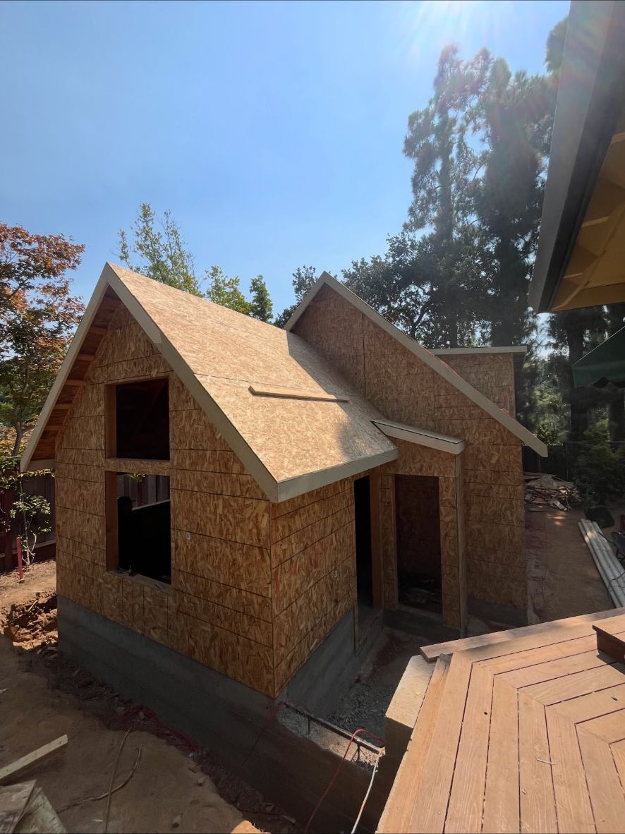 Steep gable roof sheathed on a new accessory dwelling unit beside a redwood deck