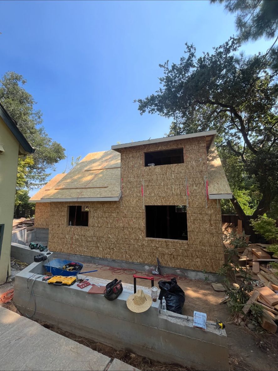Two-story accessory dwelling unit sheathed and dried in on a new stem wall foundation under valley oaks