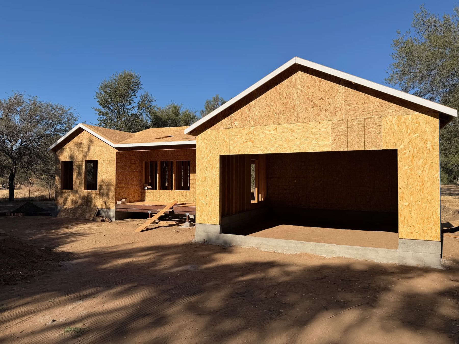 Sheathed custom home and attached garage with the gable roof framed on a Northern California lot