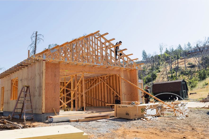 Framed and sheathed garage with roof trusses being set by a Lane Built crew on a foothill lot