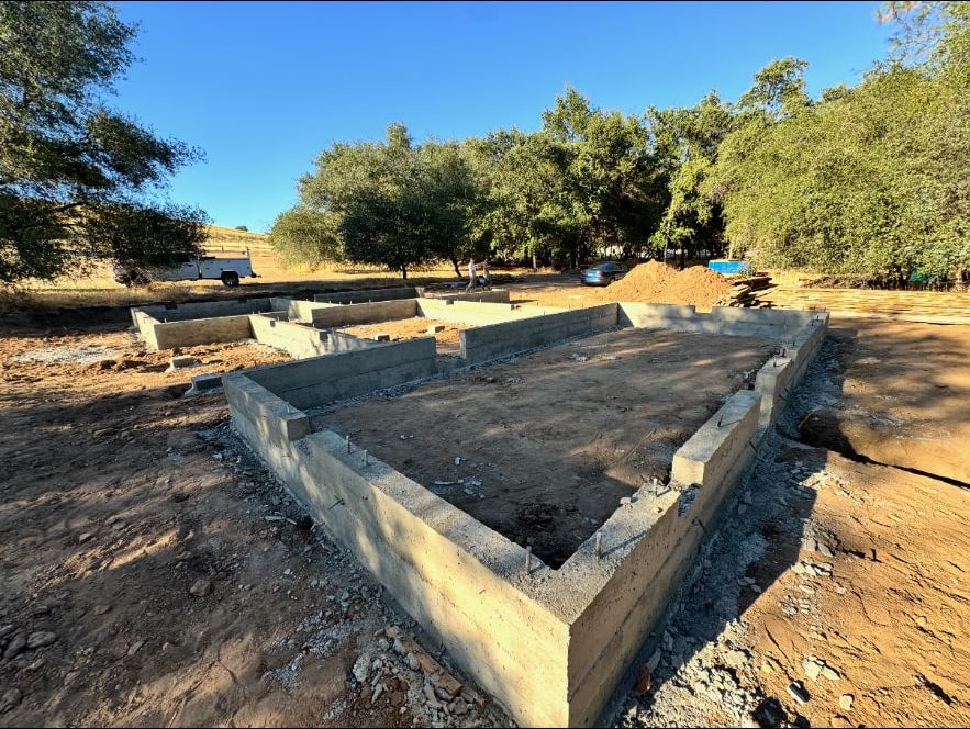 Poured concrete stem wall foundation with anchor bolts set for a custom home on an oak studded lot