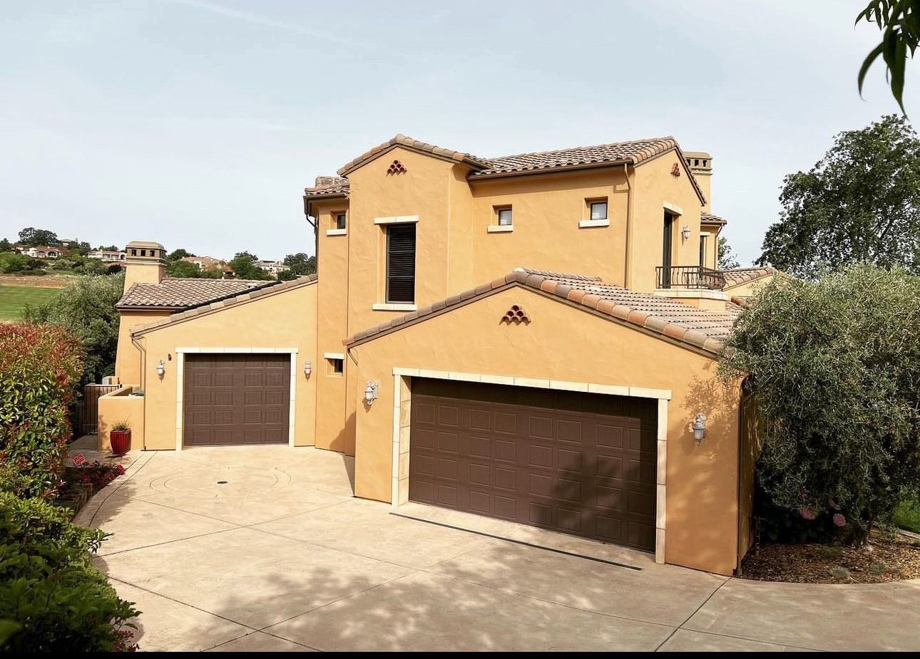 Tuscan style custom home in golden stucco with a clay tile roof and stamped concrete drive above a Northern California golf course
