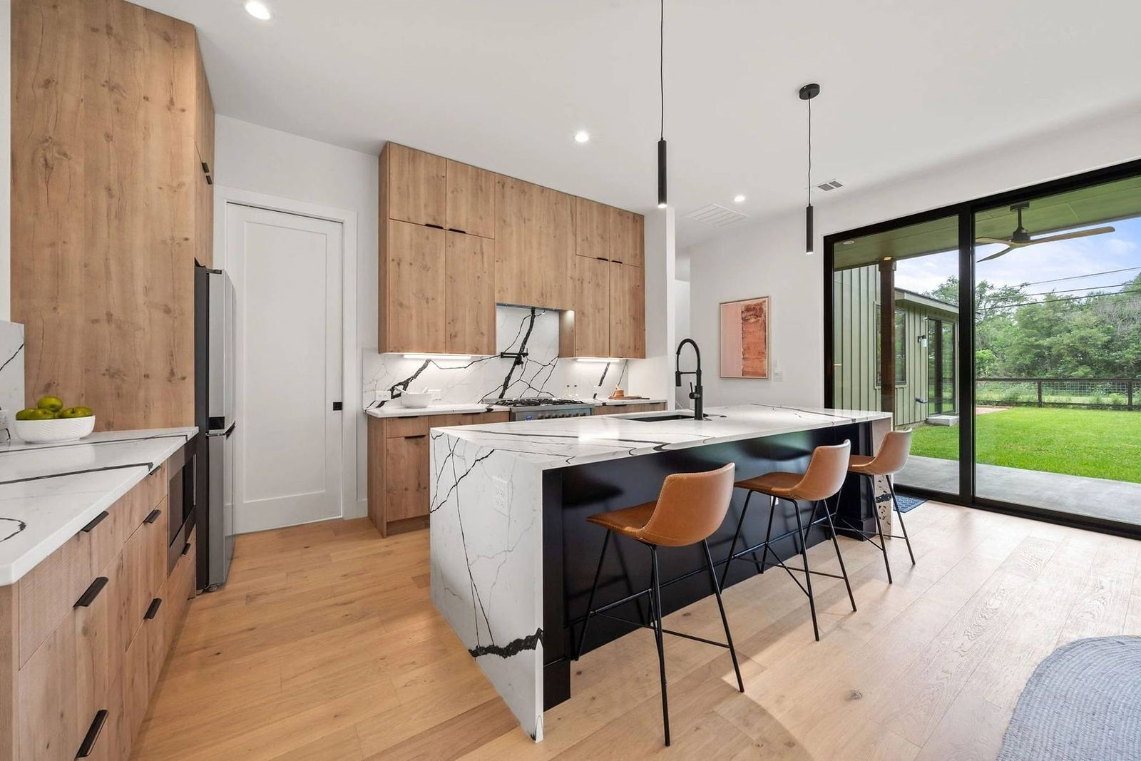 Marble waterfall island with leather barstools and warm wood cabinetry in a Placer County kitchen renovation