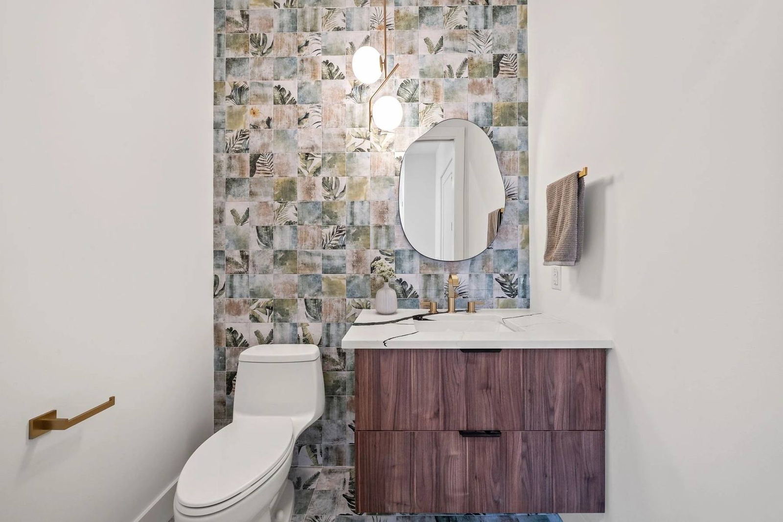 Powder bath with patterned tile feature wall, floating walnut vanity and round mirror