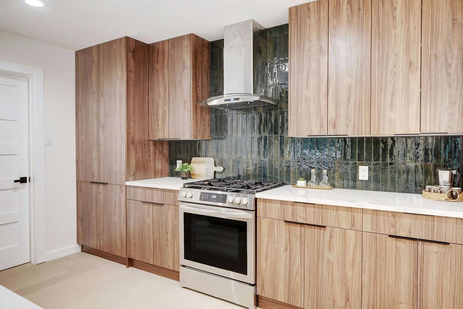 Walnut cabinetry, quartz counters and glazed green tile backsplash