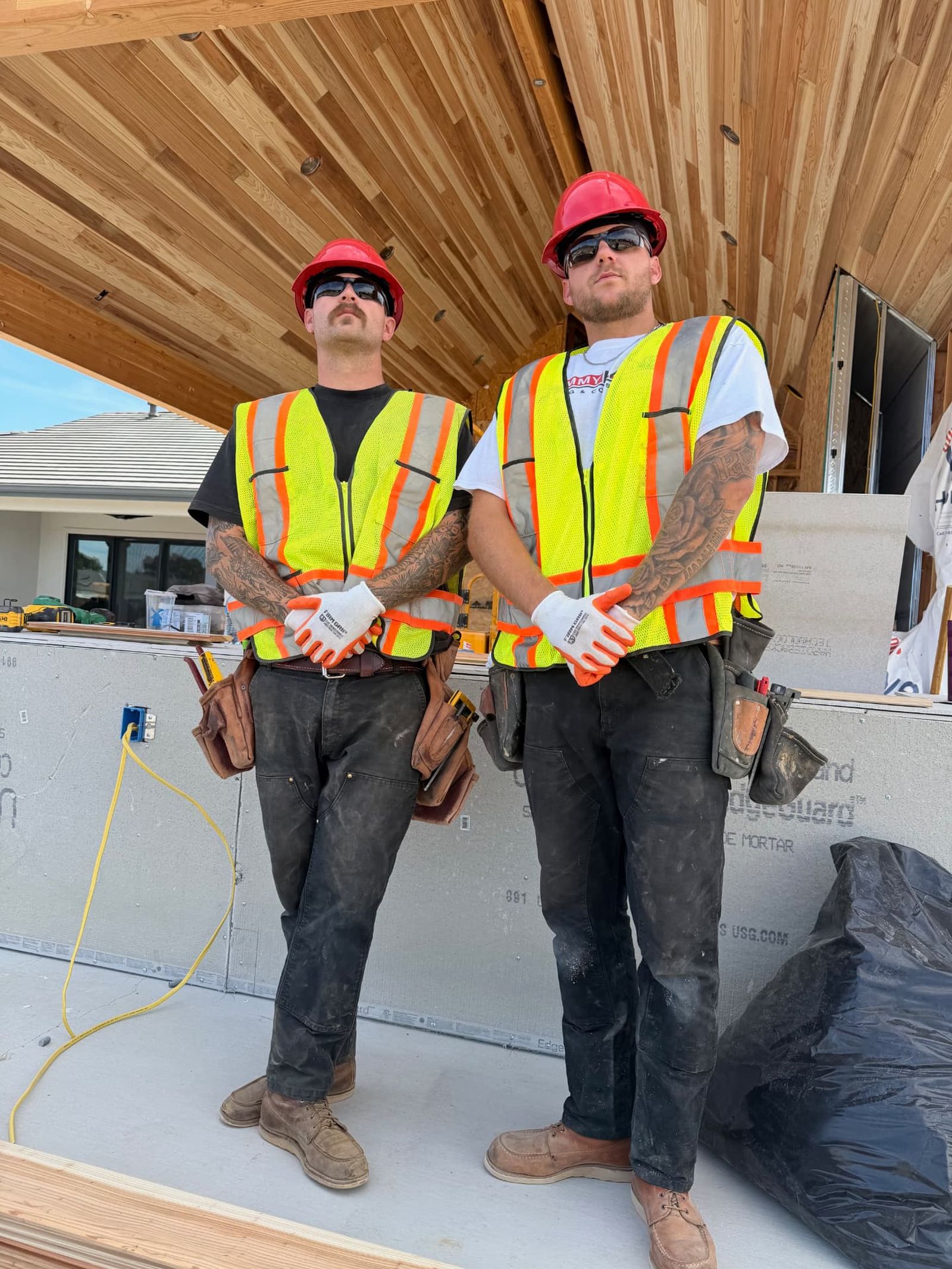 Two Lane Built Inc. carpenters in safety vests under a finished cedar porch ceiling