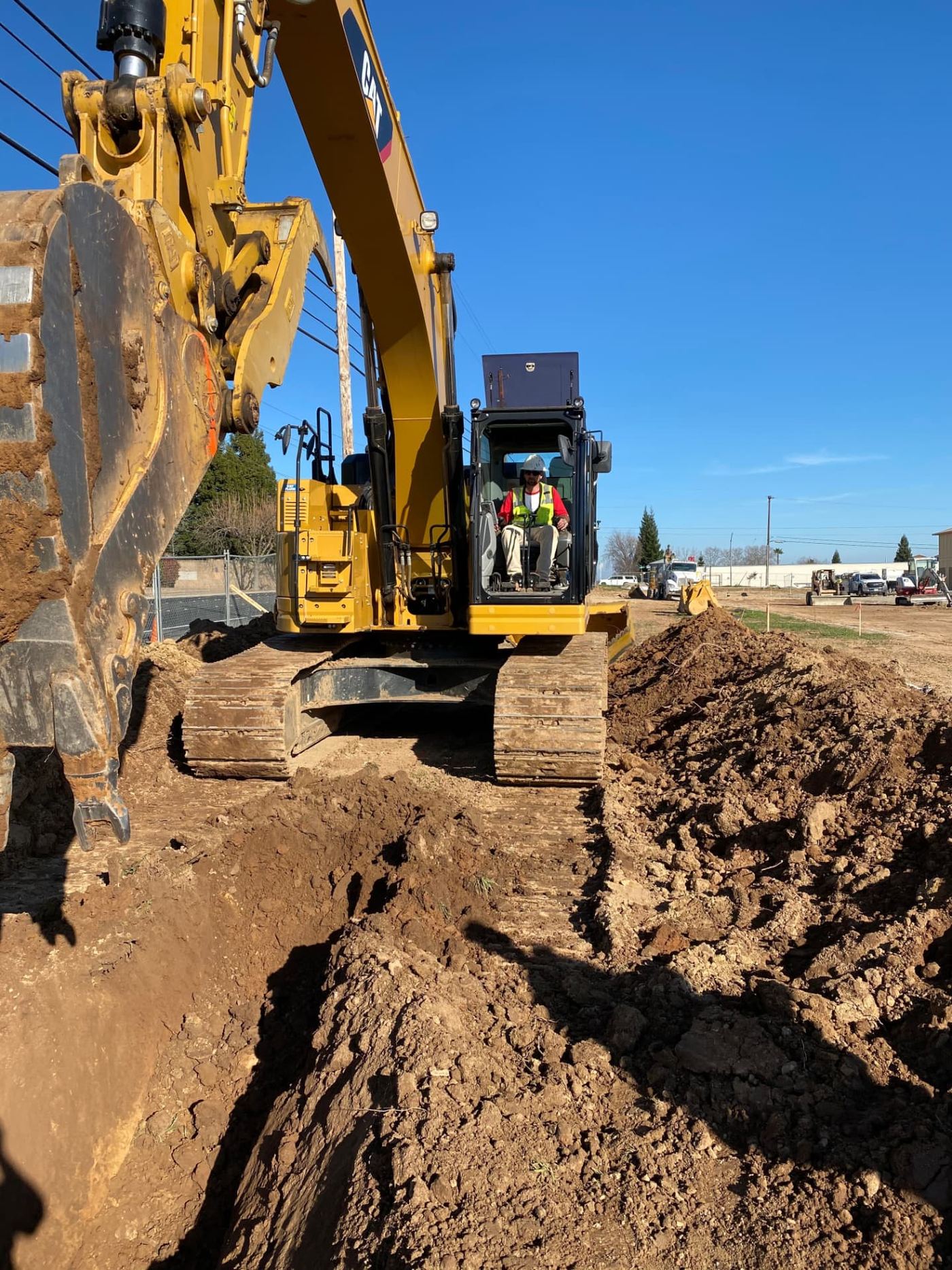 Lane Built Inc. operator running a Cat excavator on a utility trench