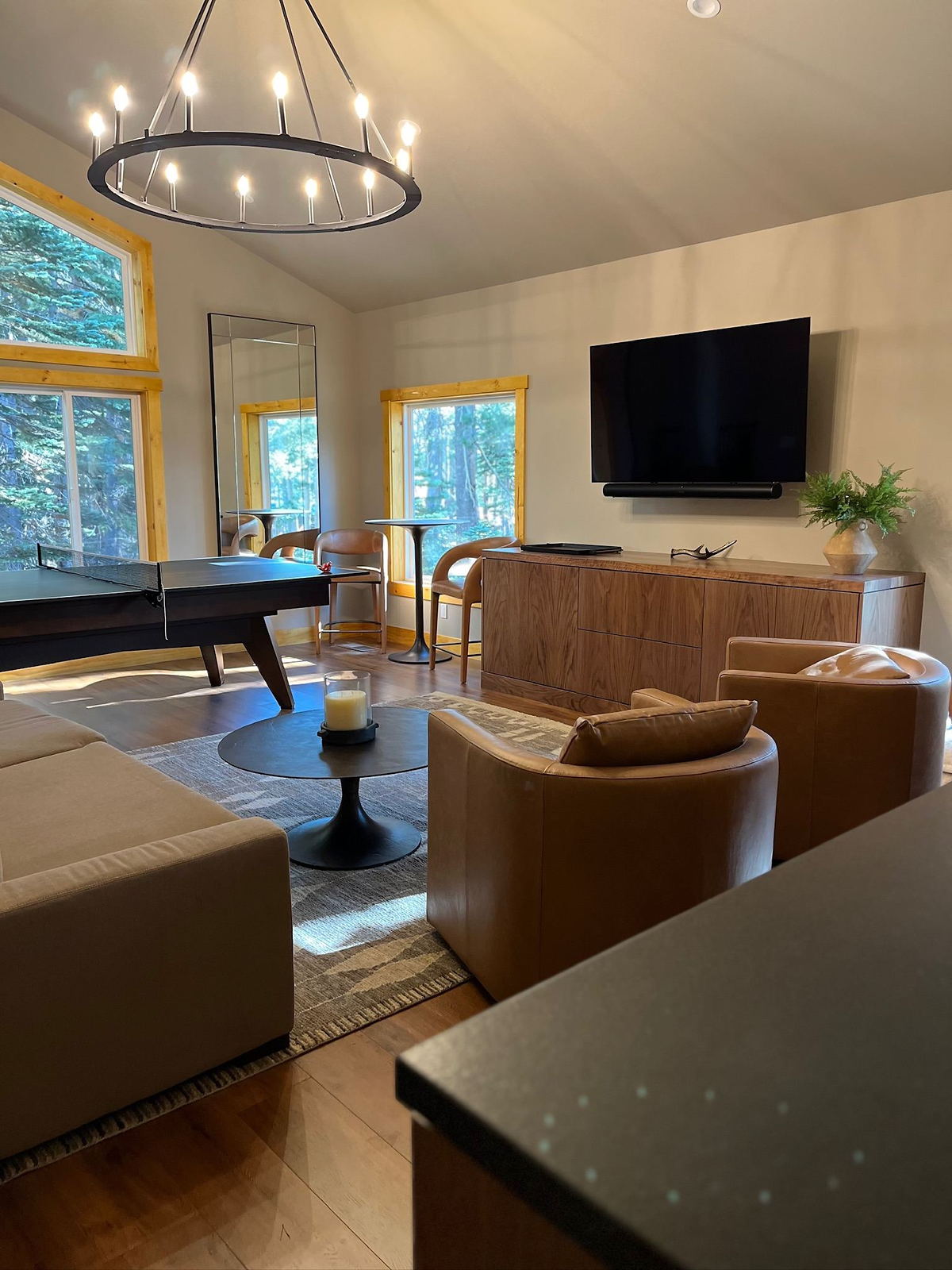 Living room with leather seating, oak floors and a vaulted ceiling