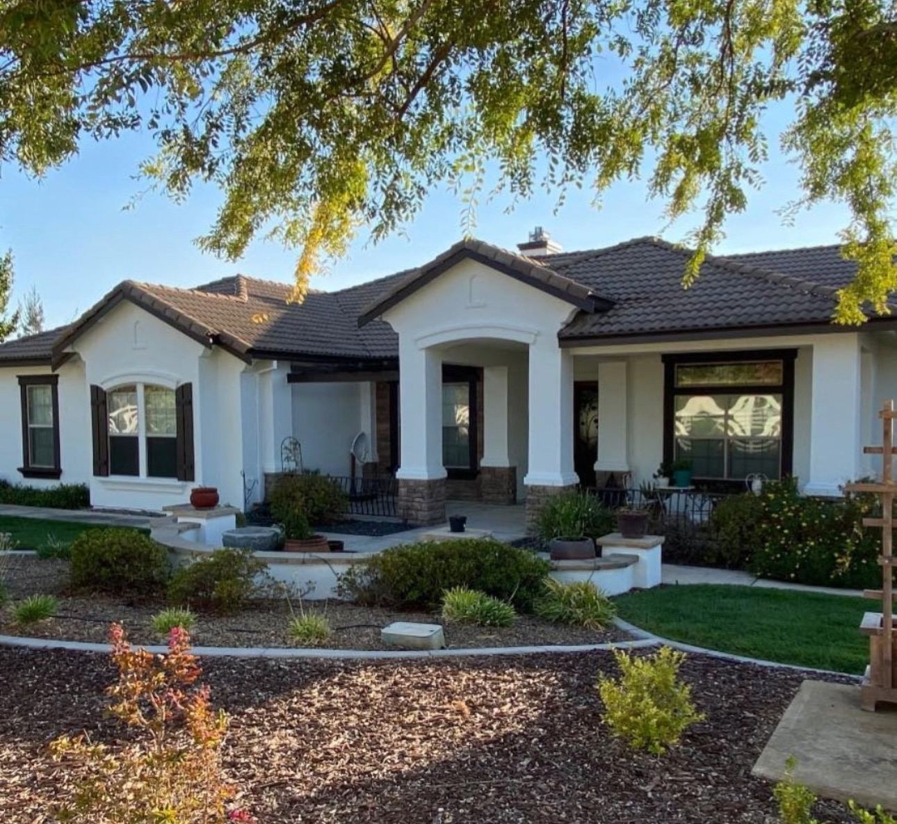 Single-story ranch home with white stucco and stone wainscot after an exterior repaint