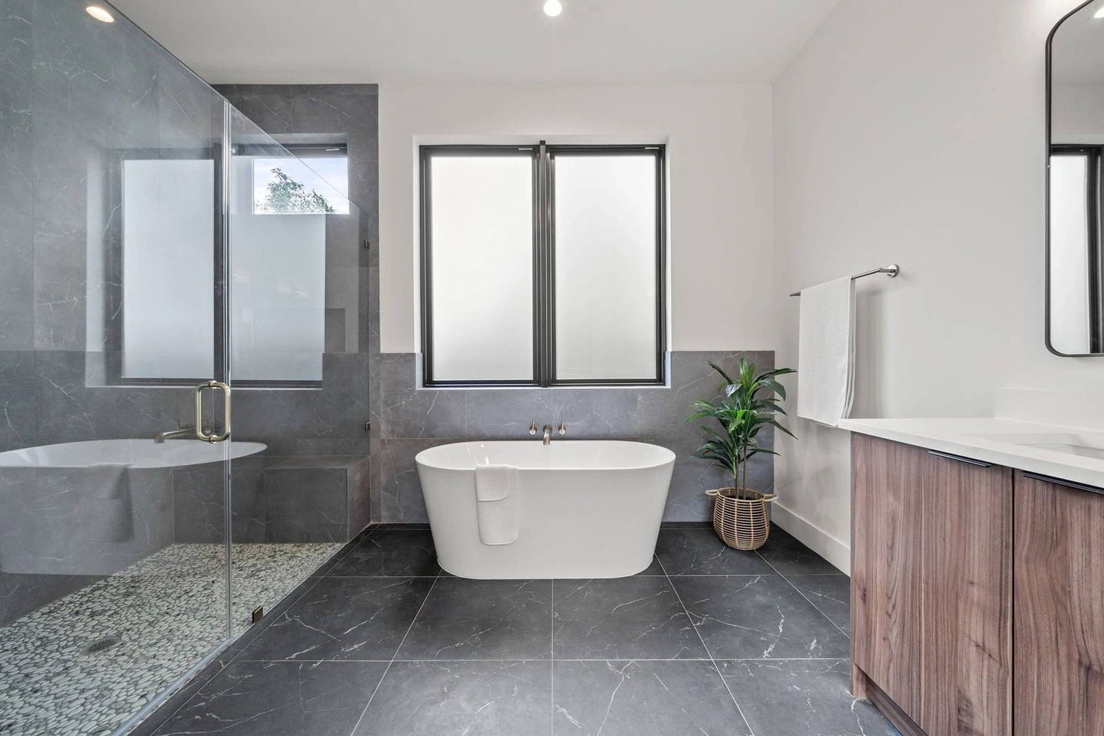 Primary bathroom with freestanding soaking tub and walnut vanity